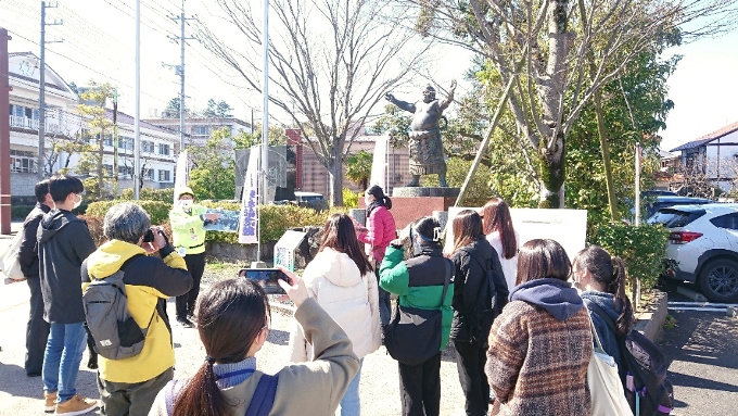 ▲赤瓦にある倉吉出身の元力士・琴桜の銅像前で説明を聞いている学生たち